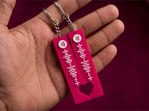 Pair of pink song code keychains held in a hand