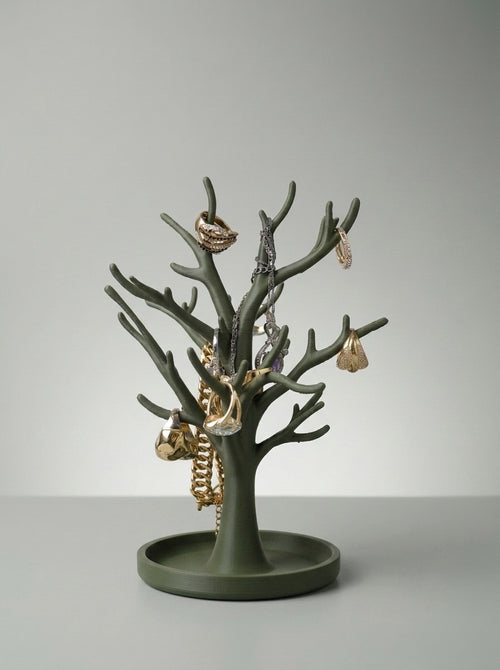 Green tree jewelry stand holding rings, earrings and a chain bracelet